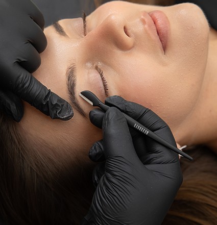 A model laying down getting their brow trimmed with an eyebrow razor