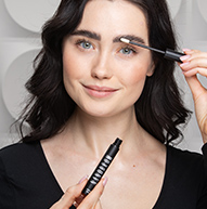 Smiling model applying eyebrow conditioner