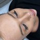 A woman in a black shirt shows off her long eyelashes, highlighting her DIY eyelash extensions.
