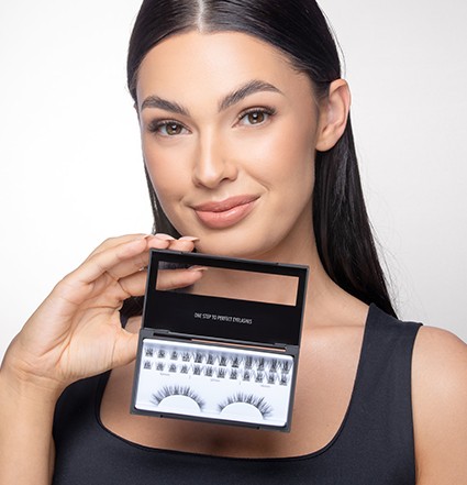 امرأة ذات شعر أسود تبتسم وتحمل مجموعة وصلات الرموش